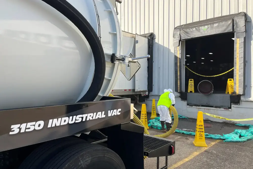 3150 industrial vacuum truck with operator feeding yellow hose into loading dock, Cusco industrial vacuum equipment