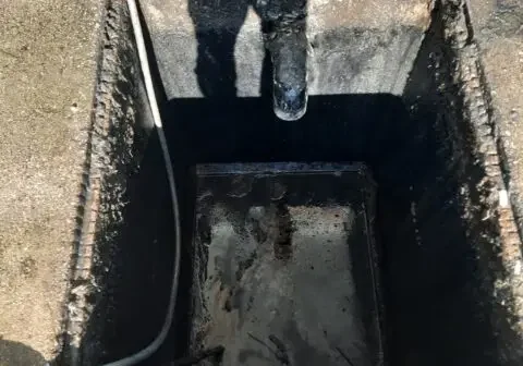 Open rectangular underground pit with hose and inlet pipe, staged for Cusco vacuum truck service.